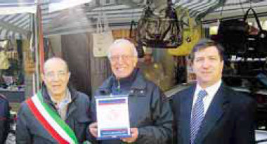 Francesco Melpignano premiato dal sindaco Gustavo Maccari e dal presidente della Pro loco Lorenzo Aresi per i 68 anni di presenza della sua bancarella alla Fiera