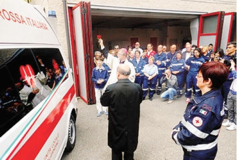 Monsignor Coter benedice la nuova ambulanza, con una rosa rossa